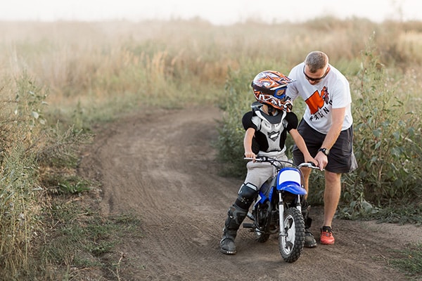 Ein Junge auf einem Kinder Motocross erhält Anweisungen von seinem Trainer