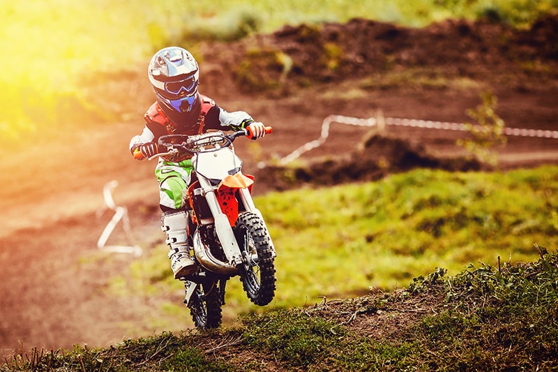Kleiner Junge mit Mini Motocross auf einer Rennstrecke
