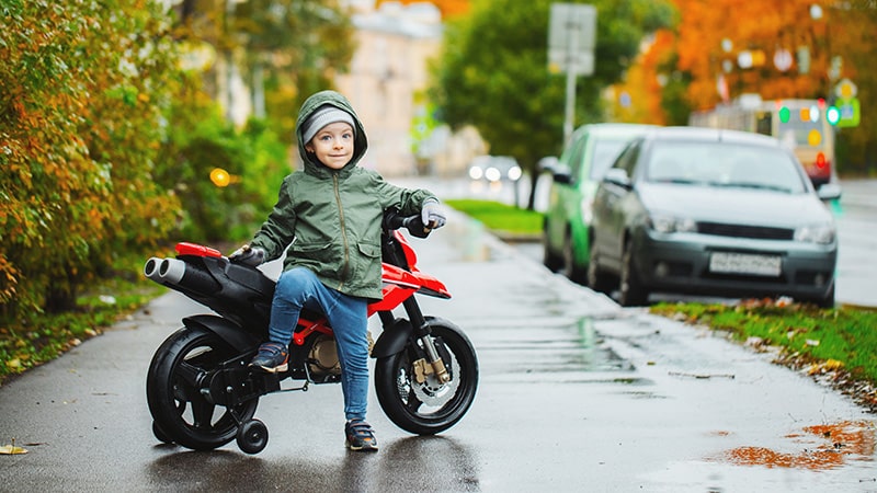 Kleiner Junge posiert an seinem roten Kindermotorrad